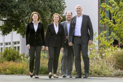 Zwei Frauen und zwei Männer im Anzug stehen in der Position als  Geschäftsführung vor dem Firmengebäude der Roth Industries